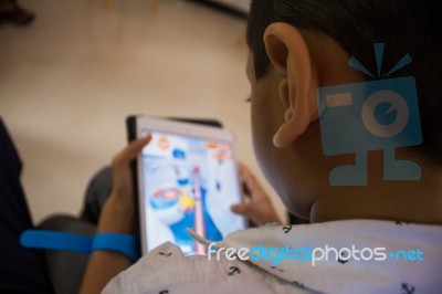 A Little Boy Playing A Game On His Tablet Stock Photo