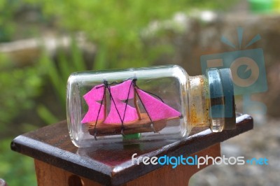 A Miniature Ship Inside The Bottle. In The Photo Very Close To A Charming Garden Background Stock Photo