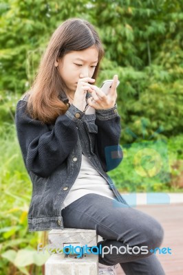 A Young Girl Using Smartphone In Park Stock Photo