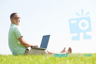 A Young Men Sit On The In The Park Using A Laptop Stock Photo