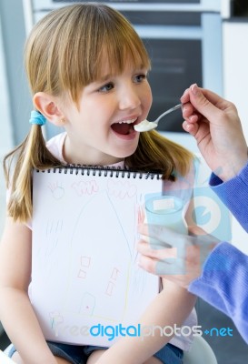 A Young Woman And Little Girl Eating Yogurt In The Kitchen Stock Photo