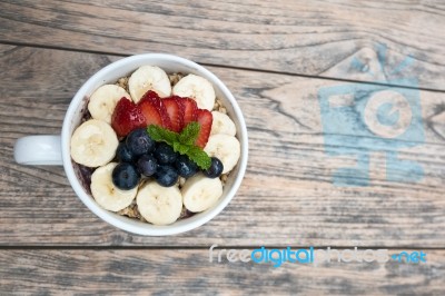 Acai Bowl With Fresh Fruit Strawberry, Blueberry, Banana And Peppermint Leaves On Top On The Wooden Table Stock Photo