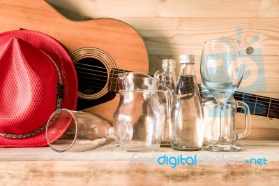 Acoustic Guitar And Assorted Glass Bottles On Wooden Table. Retr… Stock Photo