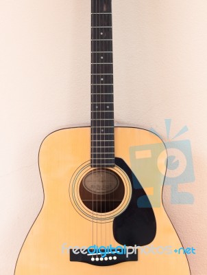 Acoustic Guitar On Orange Wall Background Stock Photo