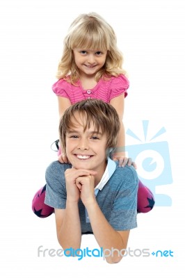 Adorable Sister Sitting On Her Brothers Back Stock Photo