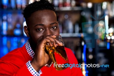 African Guy Drinking Beer, Blur Background Stock Photo