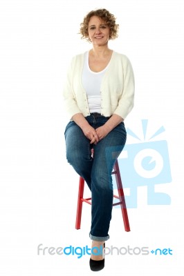 Aged Woman Sitting On Stool Stock Photo