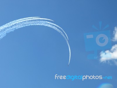 Aircrafts Drawing White Smoke Circles Into The Blue Sky Stock Photo