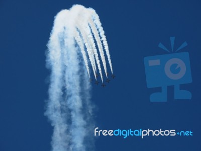 Aircrafts Drawing White Smoke Circles Into The Blue Sky Stock Photo