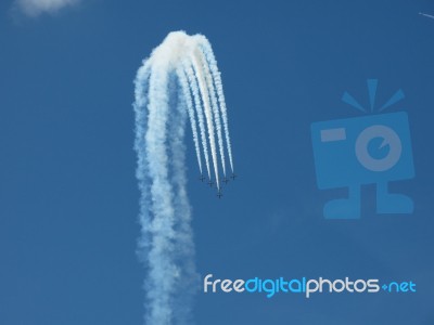 Aircrafts Drawing White Smoke Circles Into The Blue Sky Stock Photo