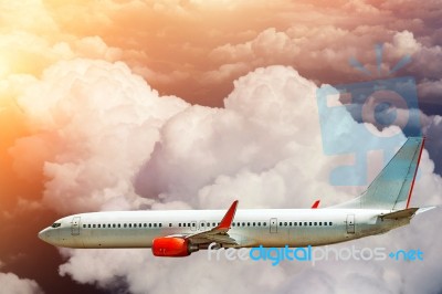 Airplane Flying Above Clouds In Sunlight Stock Photo