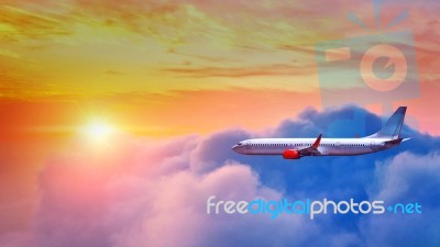 Airplane Flying Above Clouds In Sunset Light Stock Photo