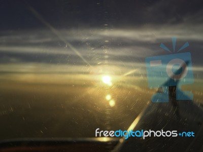 Airplane Window Focus With Sun Set On Horizon Cloud Sky Through Stock Photo