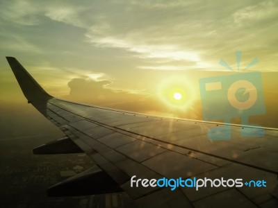 Airplane Wing In The Sky With Sun Setting In Background Stock Photo