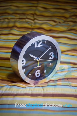 Alarm Clock On Bed Stock Photo