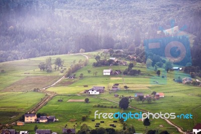 Alpine Village In Mountains. Smoke And Haze Over Hills Stock Photo