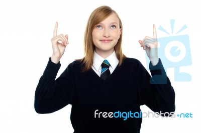 Amused Schoolgirl Looking And Pointing Upwards Stock Photo