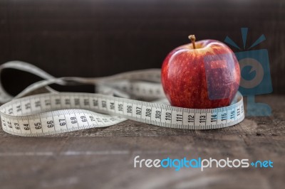 An Apple Surrounded By A Measuring Tape Tailor On Wood Stock Photo