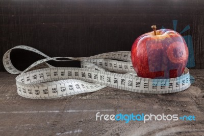 An Apple Surrounded By A Measuring Tape Tailor On Wood Stock Photo