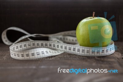 An Apple Surrounded By A Measuring Tape Tailor On Wood Stock Photo