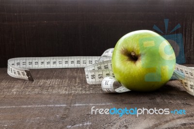 An Apple Surrounded By A Measuring Tape Tailor On Wood Stock Photo