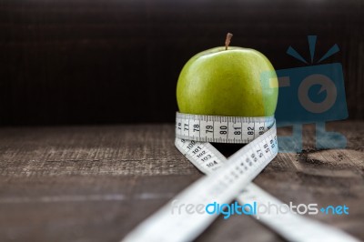 An Apple Surrounded By A Measuring Tape Tailor On Wood Stock Photo