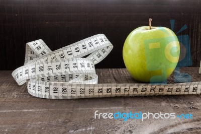 An Apple Surrounded By A Measuring Tape Tailor On Wood Stock Photo