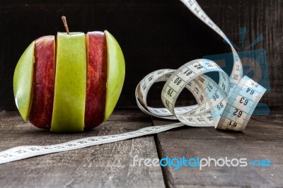 An Apple Surrounded By A Measuring Tape Tailor On Wood Stock Photo