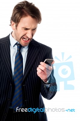 Angry Businessman Looking At His Phone Stock Photo