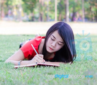 Asia Young Woman Lying On Grass Writing Book Stock Photo