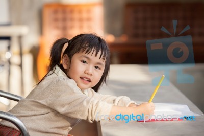 Asian Children With Yellow Pencil In Hand Doing School Home Work With Happiness Emotion Stock Photo