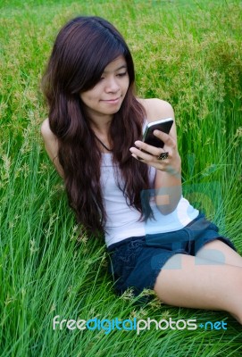 Asian Cute Girl Texting On Meadow Stock Photo