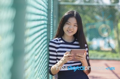 Asian Girl And Computer Tablet In Hand Standing With Toothy Smiling Face Stock Photo