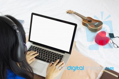 Asian Girl Sitting On Bed Surfing Internet Or Working On Noteboo… Stock Photo