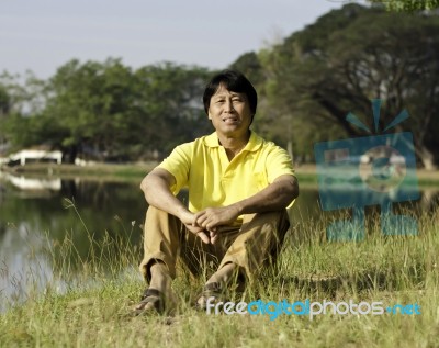 Asian Man Sitting  In The Park Stock Photo