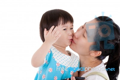 Asian Mother Carrying And Smooching Her Daughter On White Background Stock Photo