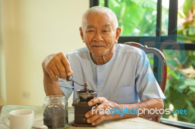 Asian Senior Man With Vintage Coffee Grinder Stock Photo