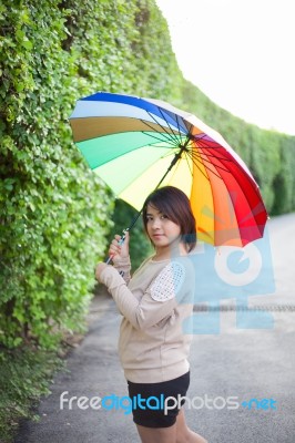 Asian Woman Holding An Umbrella On The Sidewalk Stock Photo