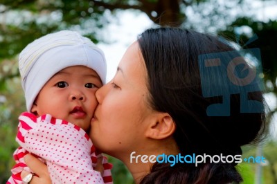 Asian Woman Kissing Her Baby Stock Photo