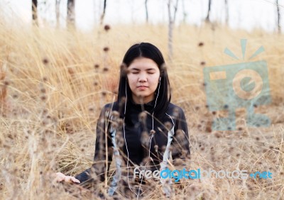 Asian Woman Meditating In Grass Field  Stock Photo