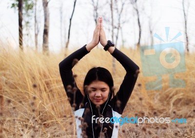 Asian Woman Meditating In Grass Field  Stock Photo