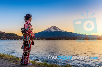 Asian Woman Wearing Japanese Traditional Kimono At Fuji Mountain. Sunset At Kawaguchiko Lake In Japan Stock Photo