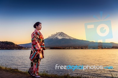 Asian Woman Wearing Japanese Traditional Kimono At Fuji Mountain. Sunset At Kawaguchiko Lake In Japan Stock Photo