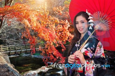 Asian Woman Wearing Traditional Japanese Kimono With Red Umbrella In Autumn Stock Photo