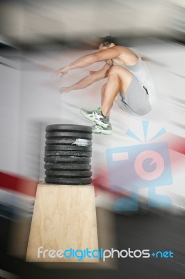 Athletic Man Jumping Over A Lot Of Weights Stock Photo