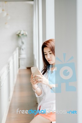 Attractive Asian Girl Sitting And Check For Email Via Smart Phone In Vacation Time Stock Photo