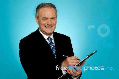 Attractive Senior Man Writing On Clipboard Stock Photo