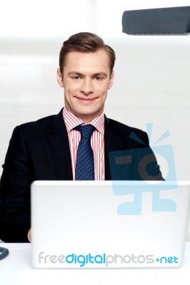 Attractive Smiling Man Operating A Laptop Stock Photo