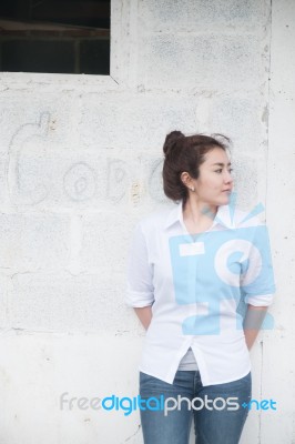 Attractive Teenage Asian Girl Standing In Front Of Grunge Concrete Wall Stock Photo