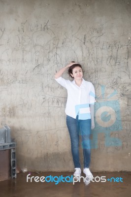 Attractive Teenage Asian Girl Standing In Front Of Grunge Concrete Wall Stock Photo